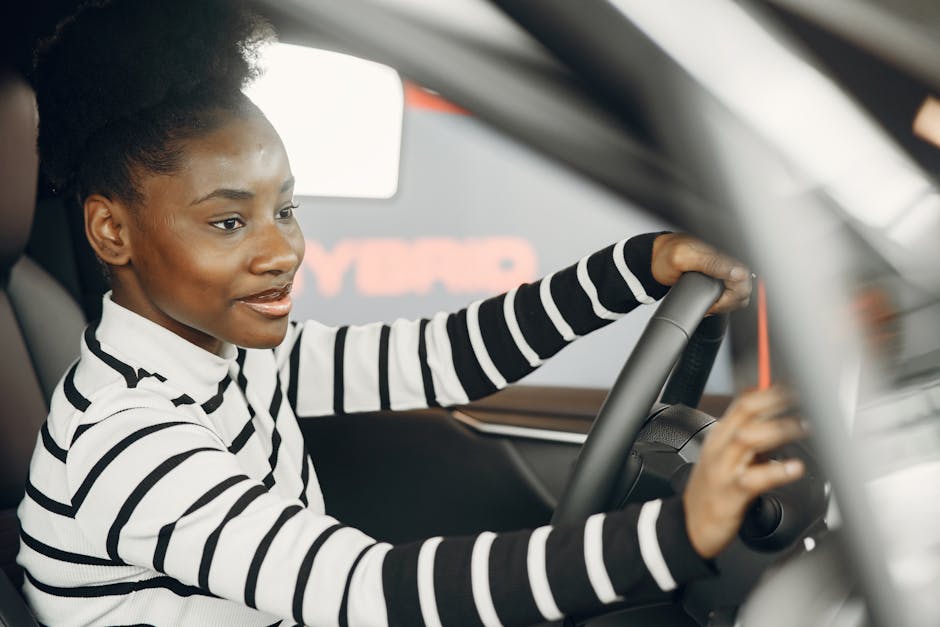 African American woman driving a car, smiling and confident behind the wheel from interior view.